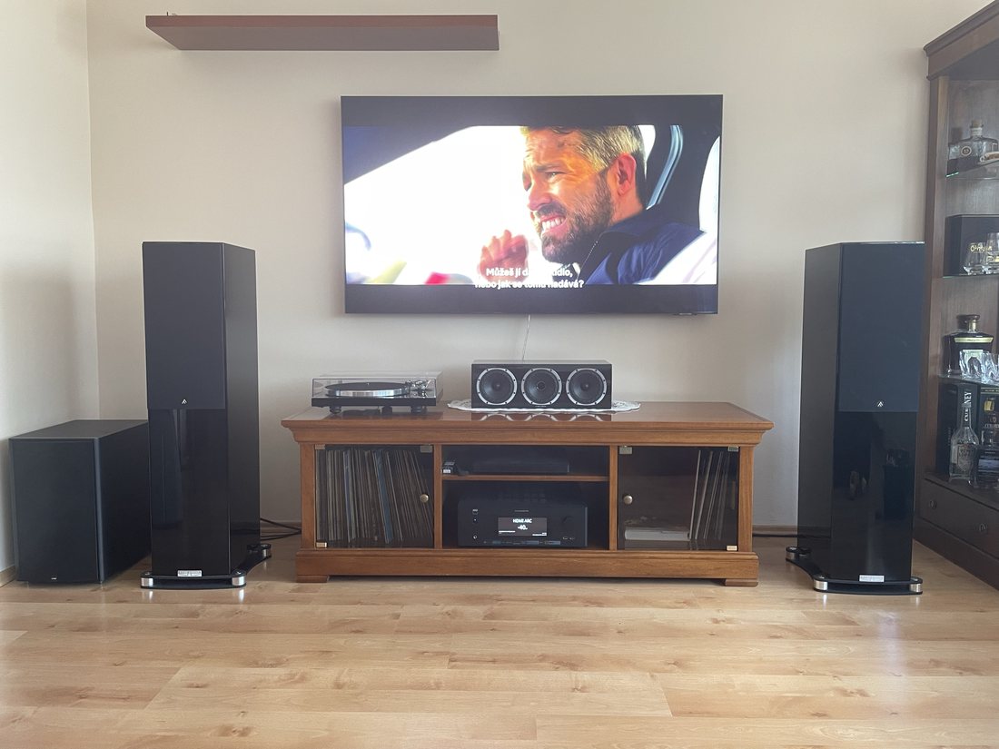 Domácí kino s televizí na zdi, gramofonem, centrálním kanálem a subwooferem