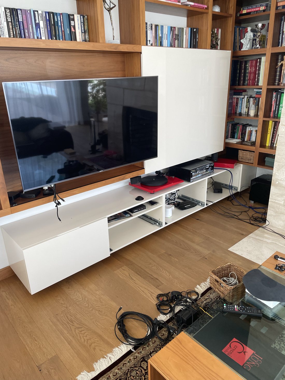 Televize v knihovní stěně s bílou AV komodou a gramofonem